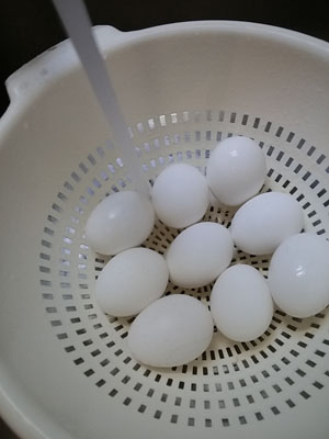 Place hard-boiled eggs in colander and rinse with cold water